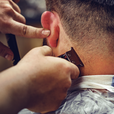 barber-gives-a-haircut-to-a-bearded-man-sitting